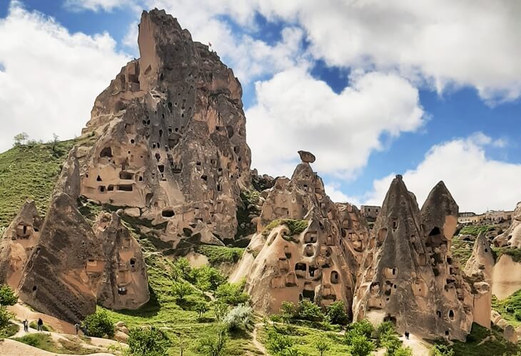 Uçhisar çevresindeki peri bacaları ve mantar şekilli kaya oluşumları, yeşil doğa ve bulutlu gökyüzüyle birlikte